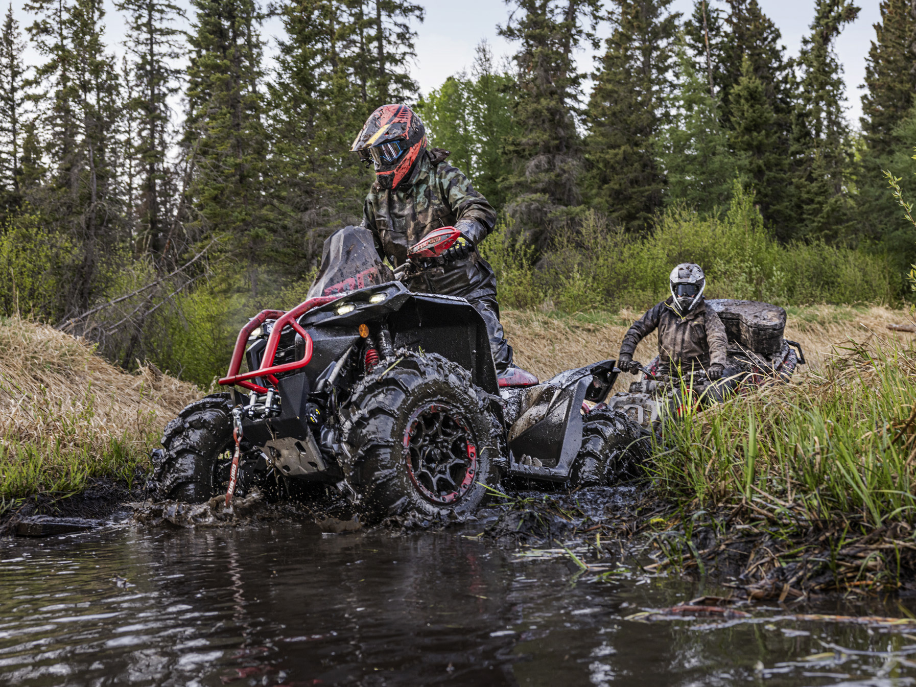 Riders on Can-Am ATVs riding through muddy stream