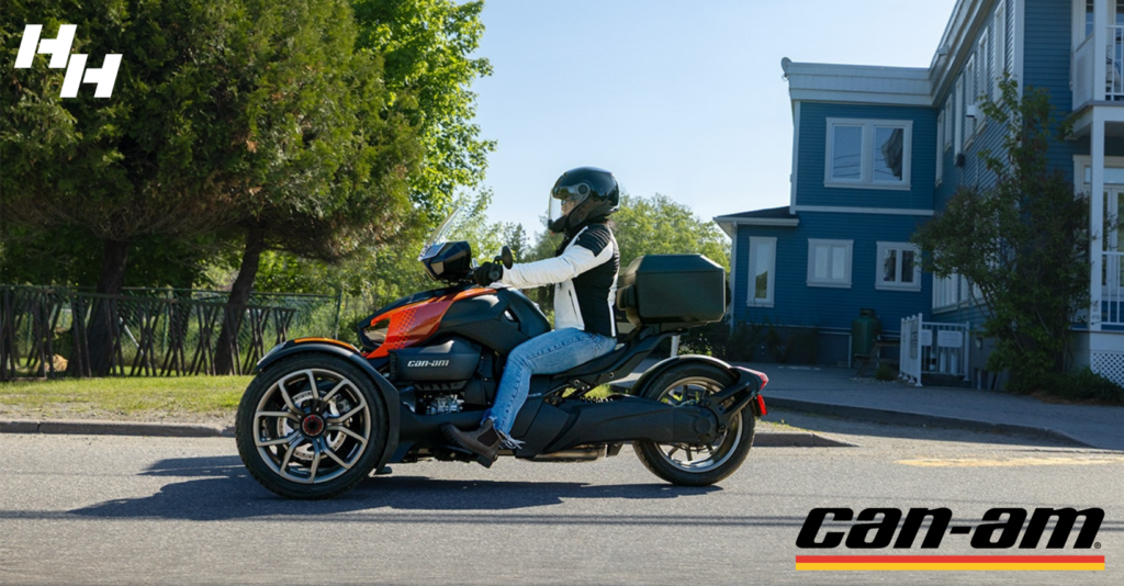 A rider parked on a Can-Am Ryker 3 wheeler near a blue house