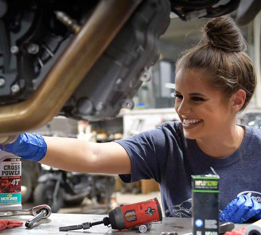 Service technician changing oil on motorcycle