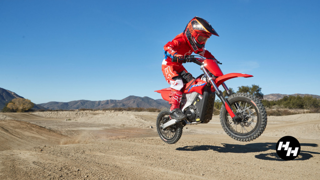 Honda CRF-E2 rider jumping a dirt hill.