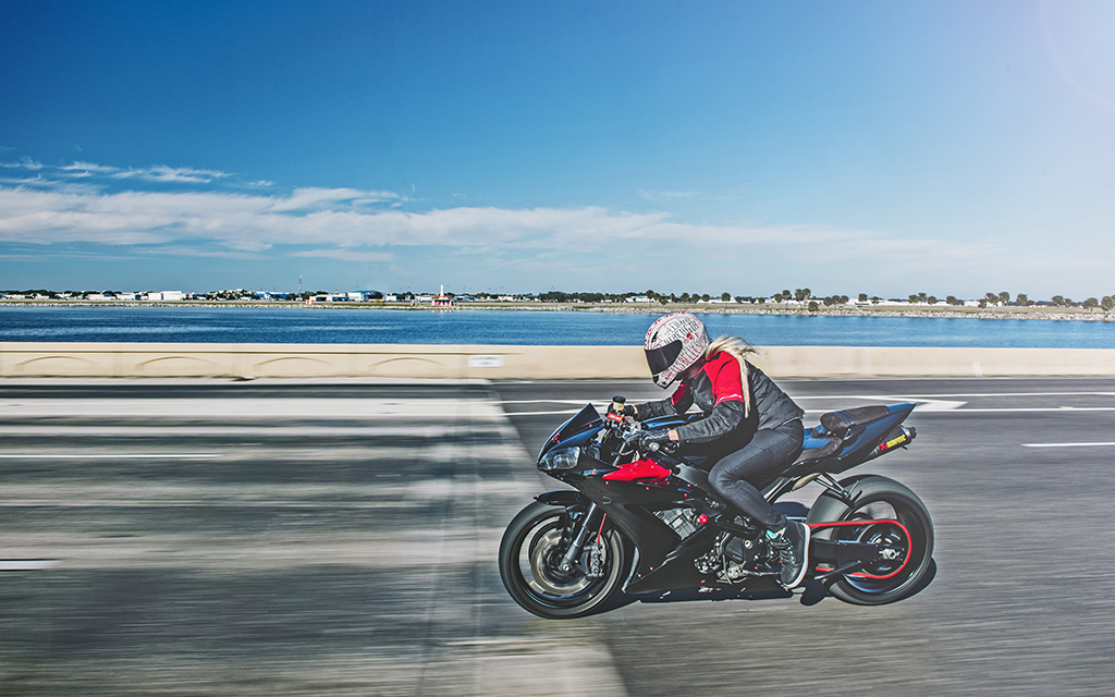 Rider speeding down highway overlooking blue lake