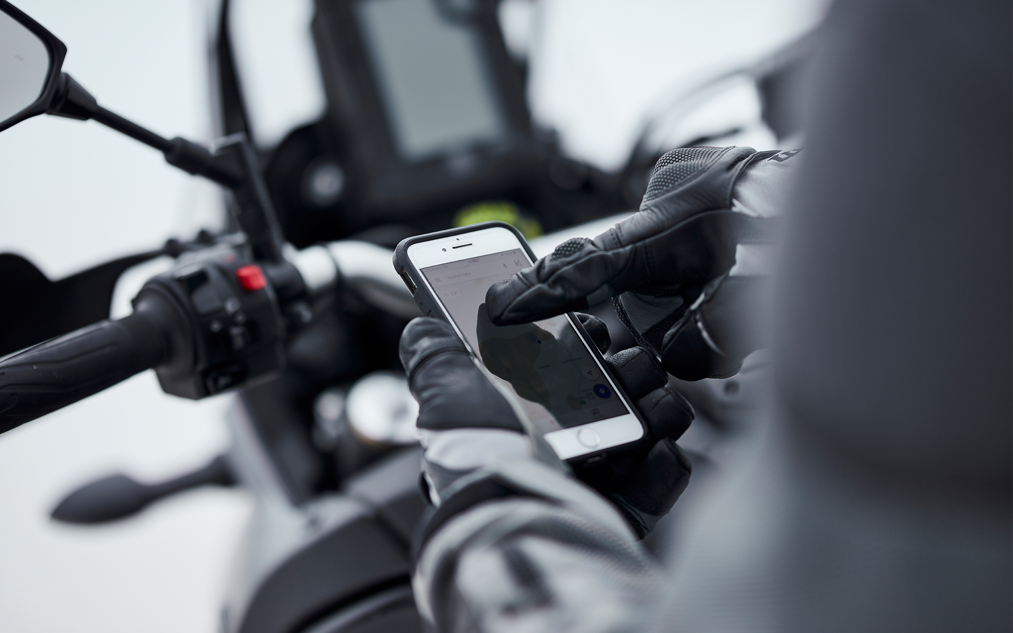 Close-up of parked motorcycle rider scrolling through phone