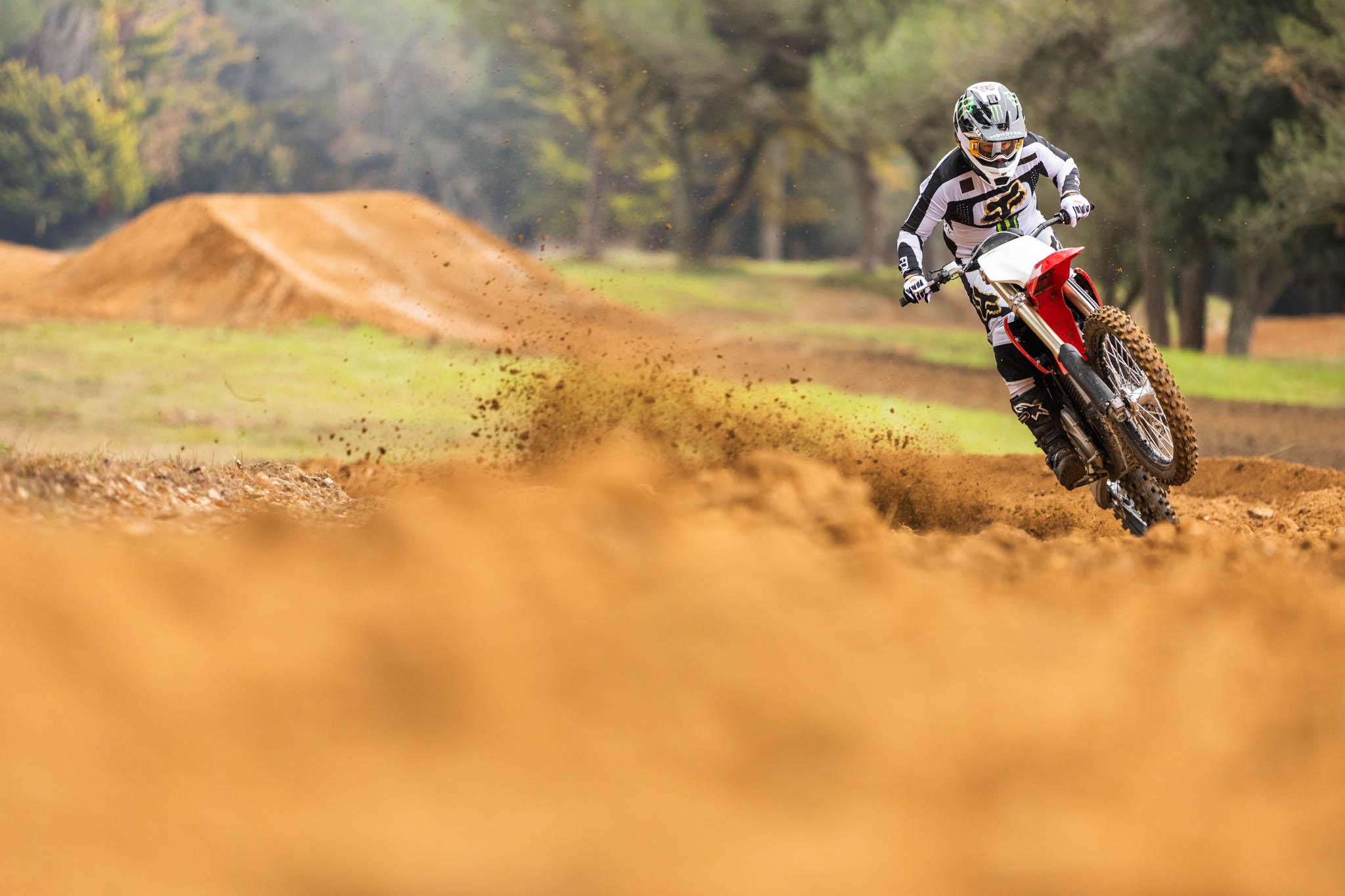 Rider on electric Stark Varg wheelies over dunes in track