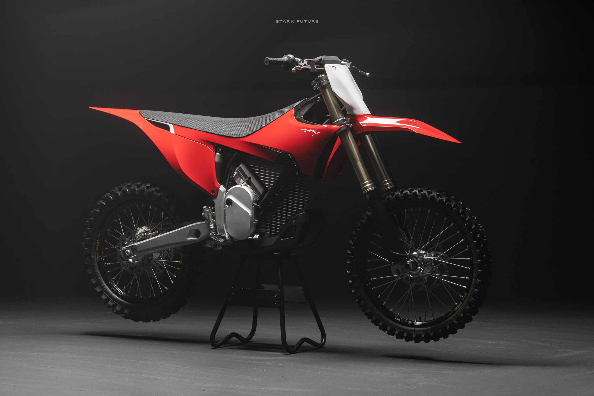 Studio photo of red Stark Varg on stand, dark background with light focused above bike